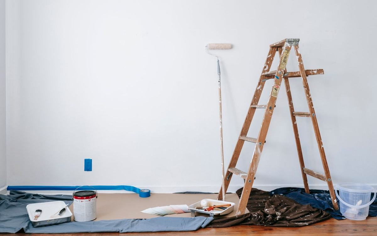 Room prepared for decorating with a stepladder, dust sheets and paint tins